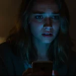 pessoa olhando para o celular abalada após ler comentários maldosos nas redes sociais