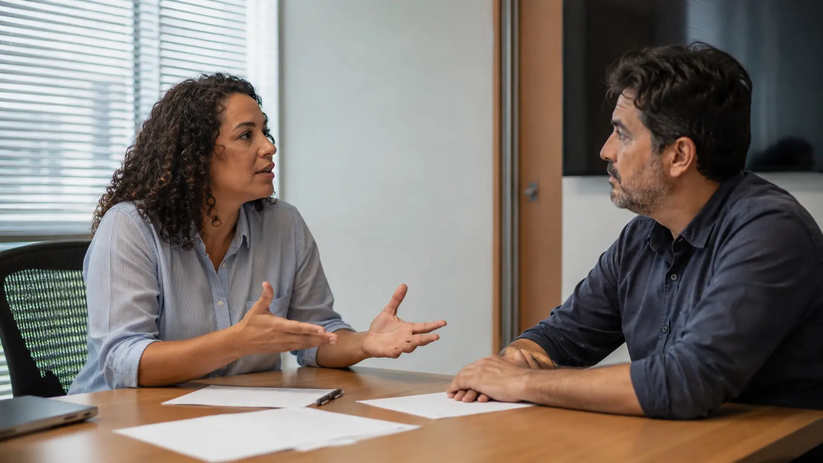 Colega gesticulando de forma insistente numa discussão enquanto o outro escuta com expressão calma sem rebater